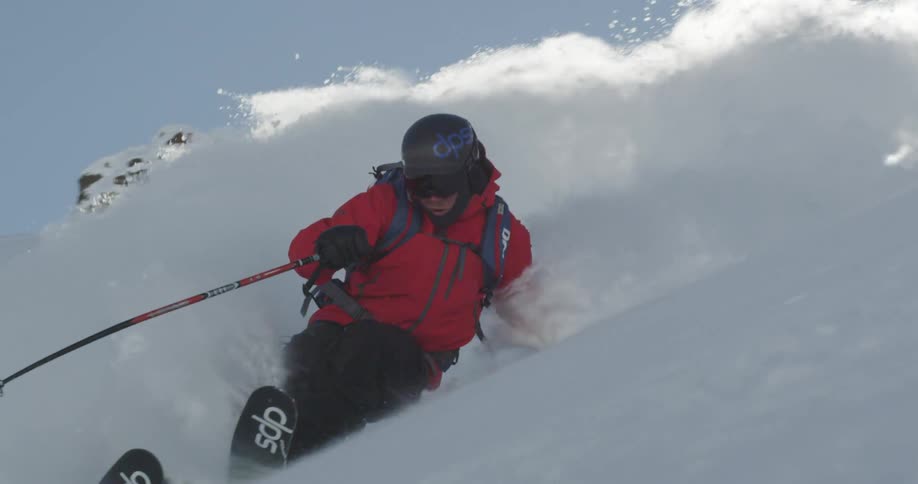 A skier sprays powder through the sun near the camera
