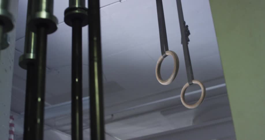 Bright lights flash in a gym where fitness rings hang from the ceiling
