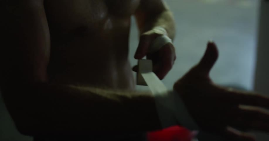 Bare chested fighter wraps his hands