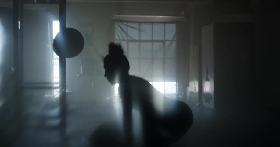 A woman lifting weights in a dark room