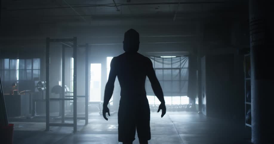 A man is stretching in the dark hall