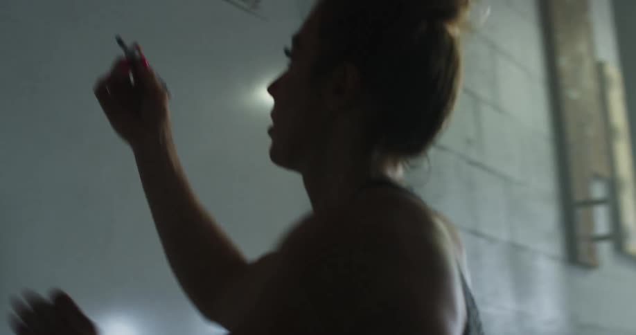 Woman with a top knot hair cleans a whiteboard with a rag and writes on a whiteboard