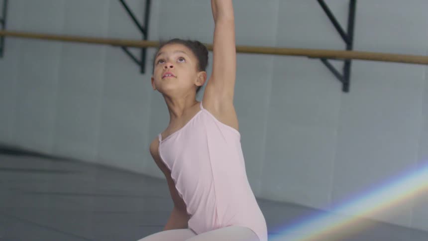 Child ballerina with a pink dress performs ballet in dance studio