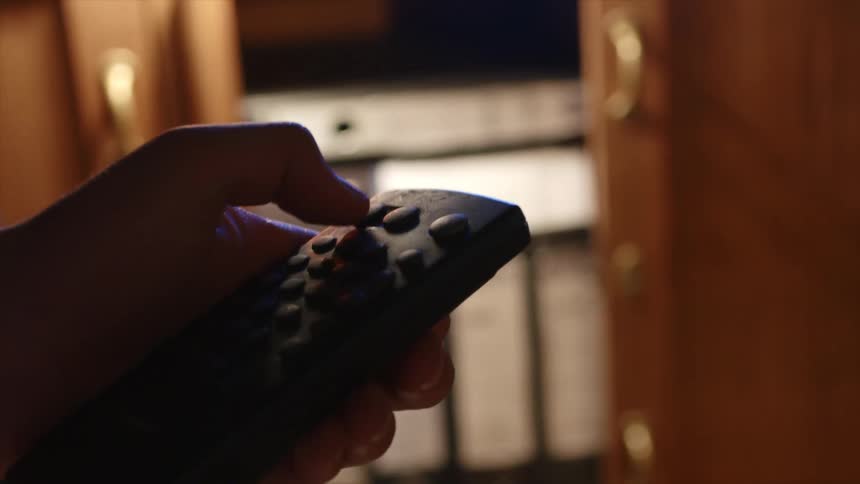 A person is pressing the buttons on a remote
