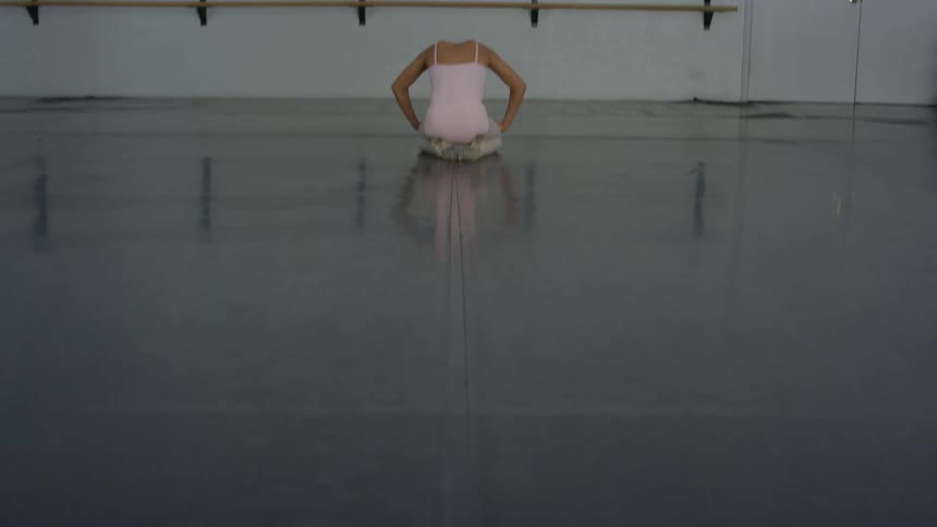 Girl sitting on floor of ballet studio lifts head