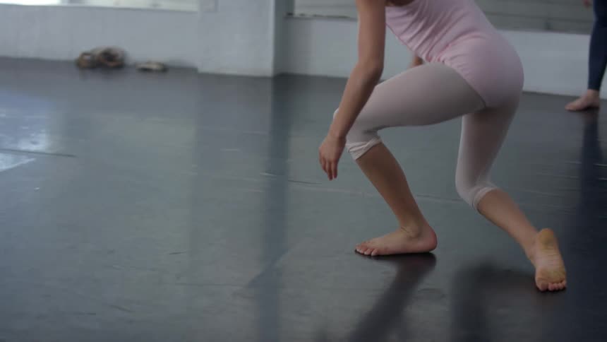 Dancers stretch in dark floored studio