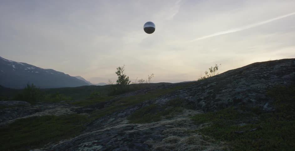 A large ball floats through the air over mountains