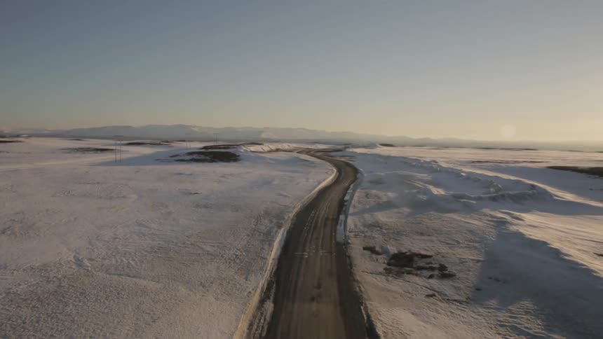 A road winds through a snow covered plain