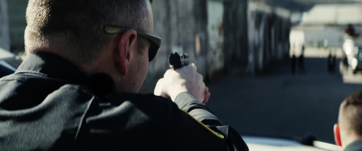 A trio of police officers take cover behind their vehicle as they aim their firearms at dark figures in an alleyway