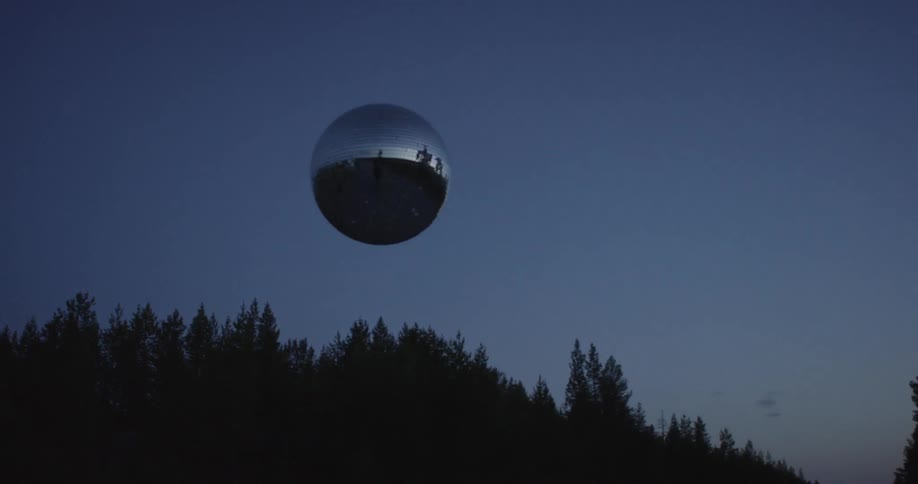 A silver orb flies near a forest