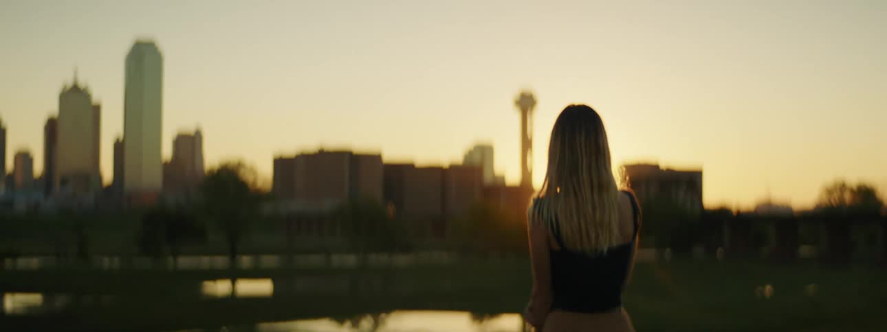 A woman is standing outdoors while looking at the city skyline