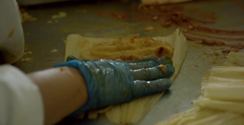 A person preparing tamales on a table