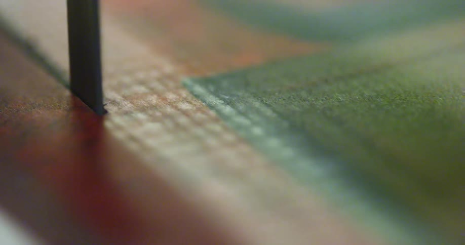 Close up of a bandsaw cutting a piece of leather like material