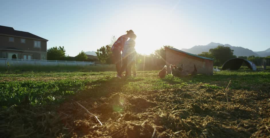 A woman and her two sons check on chickens roaming in their backyard near a chicken coop