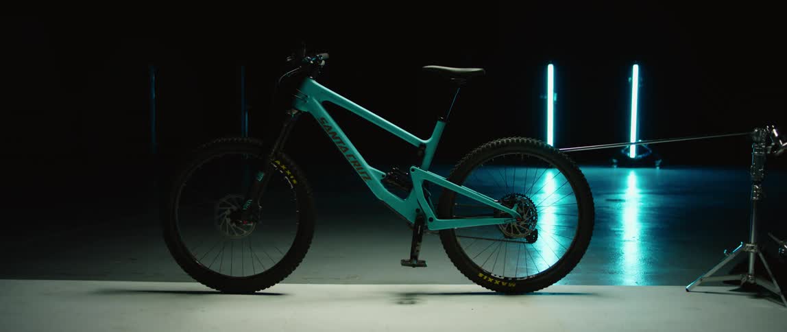 A bicycle being held upright by a stand in a dark room illuminated by a row of floor lights that switch on and off at random