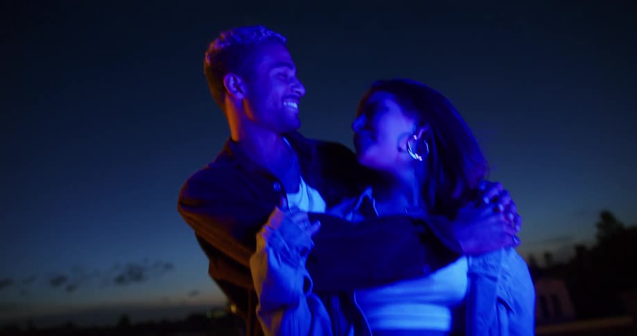 A couple outside at night holding each other and smiling