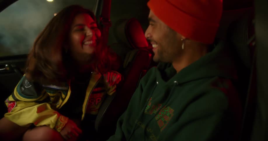 A man and woman laugh in the car
