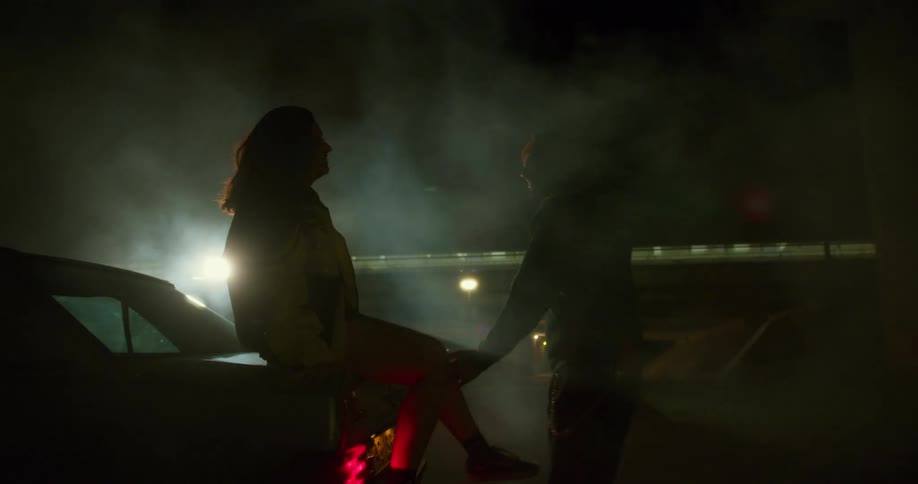 A man talks with a woman sitting on the car