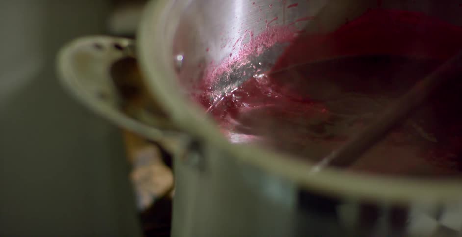 A wood spoon stirring a pot of cooking food