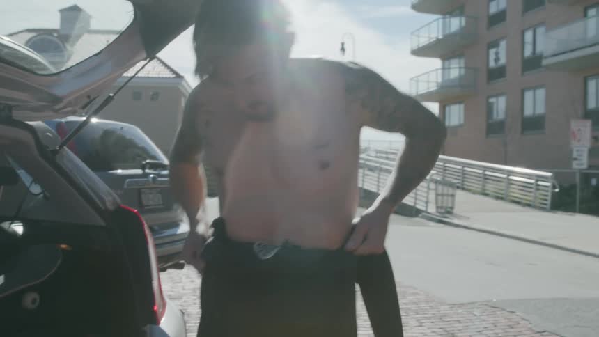 A man is adjusting a wet suit by a vehicle