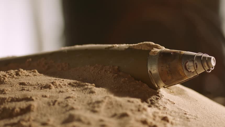 An object halfway buried in the sand with the sky and clouds in the background