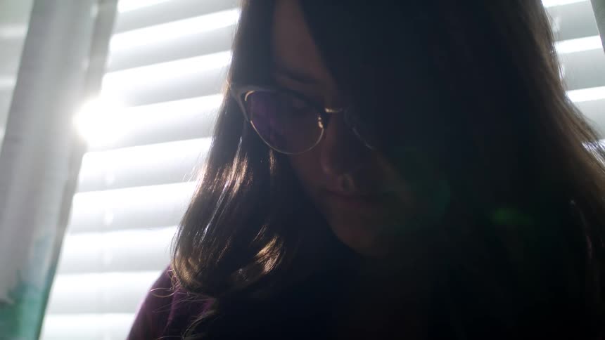A caucasian female sitting with her head down and eyes closed appearing to be sad
