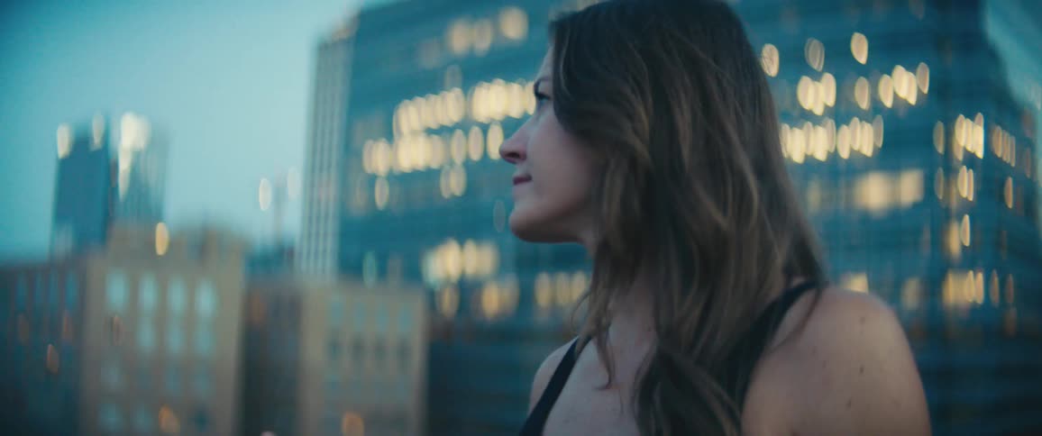 A woman walks in a downtown area with large buildings behind her