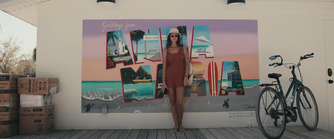 Woman poses against poster while holding phone