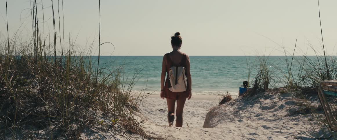 A female walking on a beach looking around