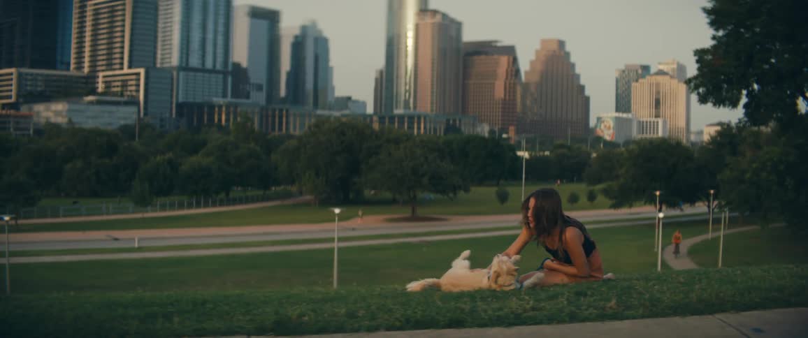 A woman is petting her dog in a city