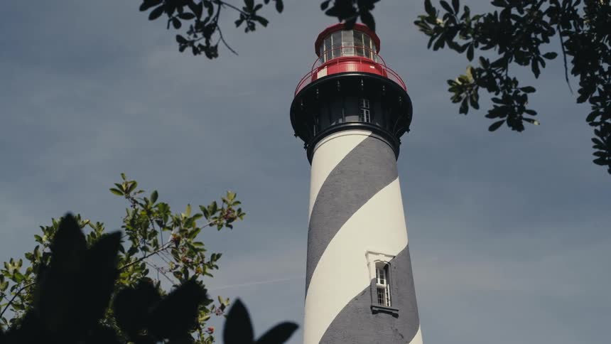 A gray and white striped lighthouse in the daytime