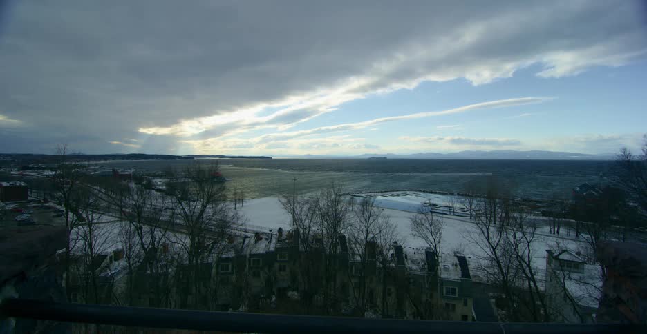 Sunlight peaks through heavy clouds over a small town in winter
