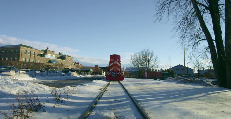 A red train sits stationary on a train track on a sunny winter day