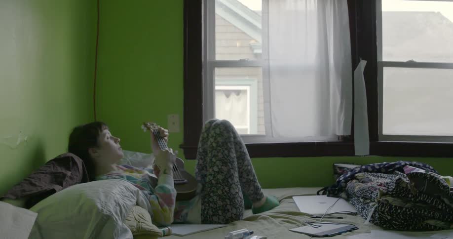 A woman playing a ukulele on a bed