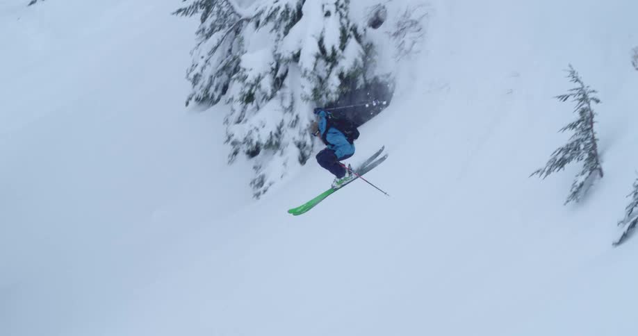 A skier speeding airs a snowy mountainside on a winter day