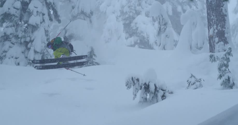 A skier doing a trick in snowy mountains during a snowstorm