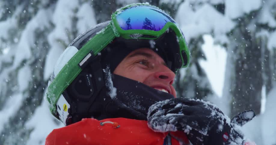 A man stands outside in the snow and smiles