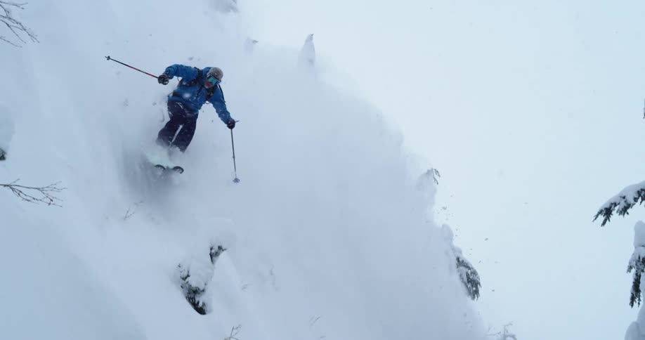 A skier turns down a steep slope in the forest