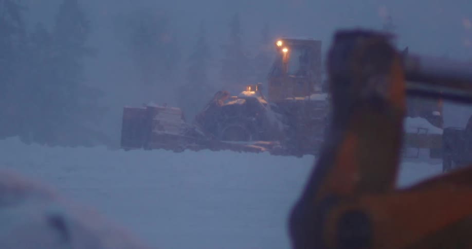 Heavy machines plow snow in the morning light