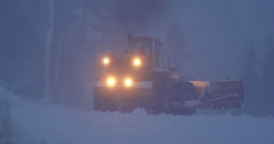 A snow plow pushes snow in the morning