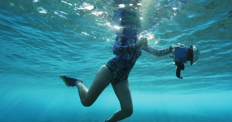 A female photographer underwater swimming with a camera