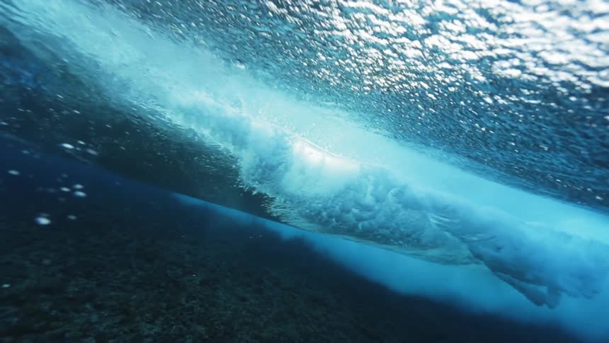 Underwater of an ocean wave curling and crashing by swimmers