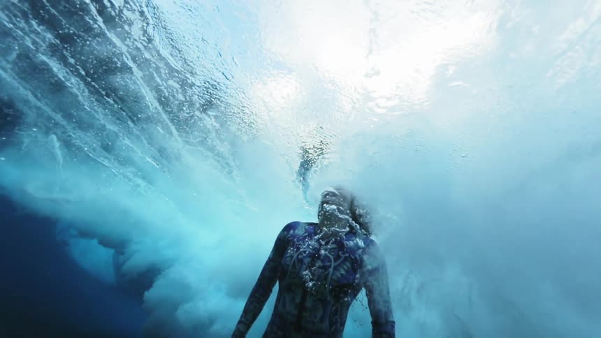 Underwater footage of a female diver rising to the surface of the shallow ocean waters