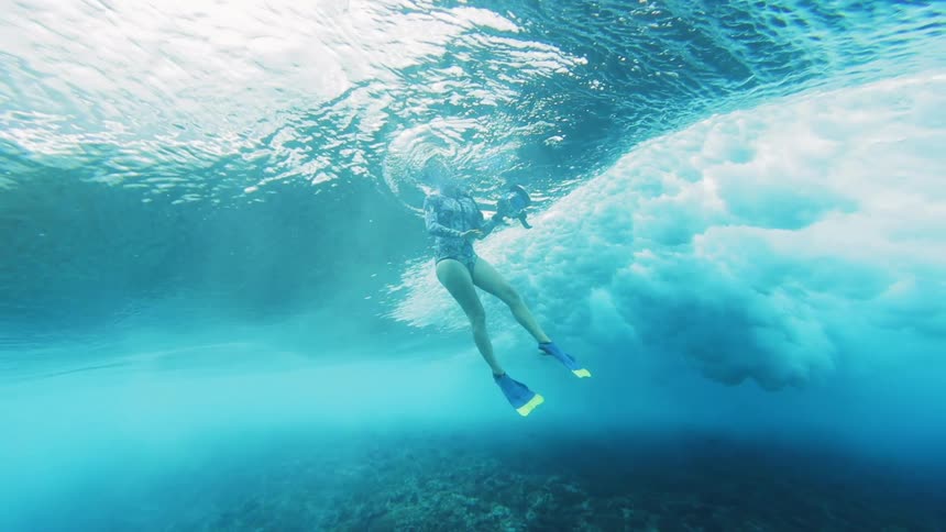 Underwater footage of a woman floating in a blue ocean