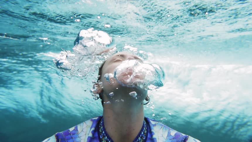 A woman under water goes up for air