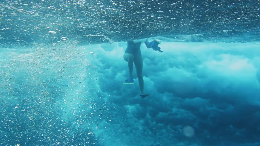 A female diver underwater as a chaotic wave rolls over her