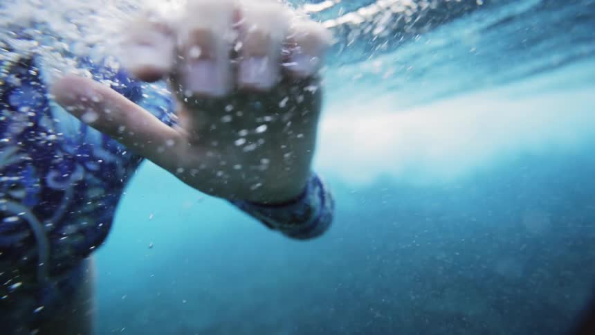 A woman under water lifts her head above the surface