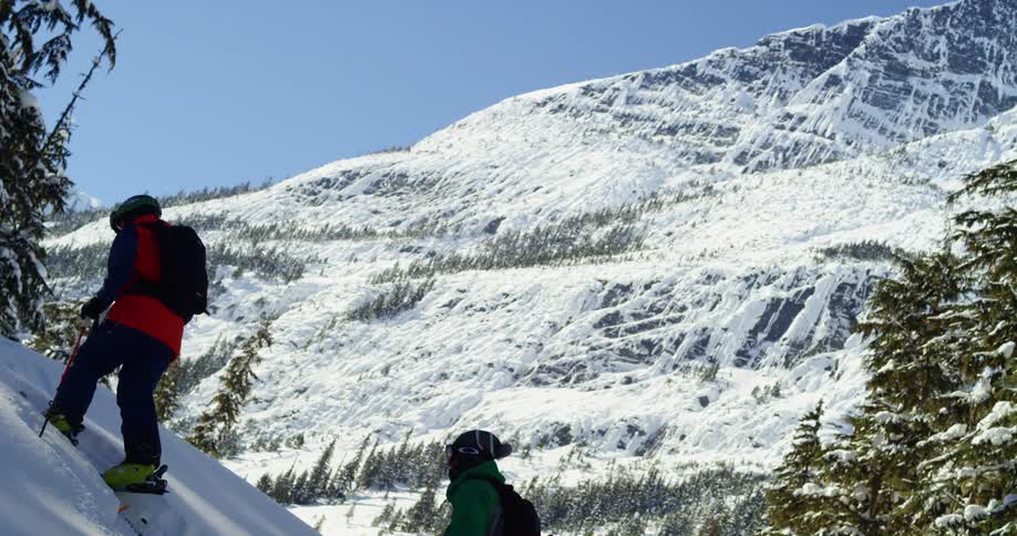 Two skiers move up a steep mountain