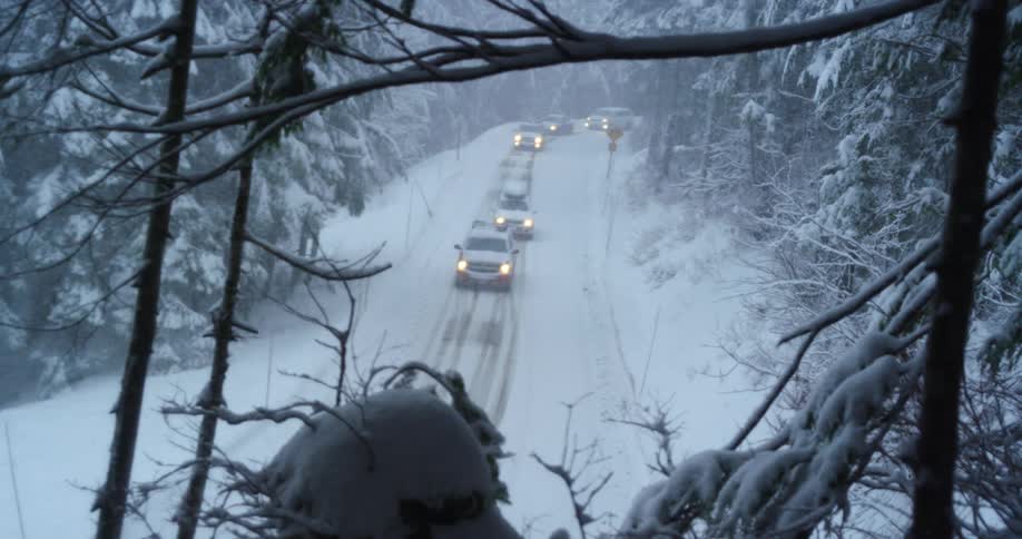 Snow falling down onto traffic on a mountain road