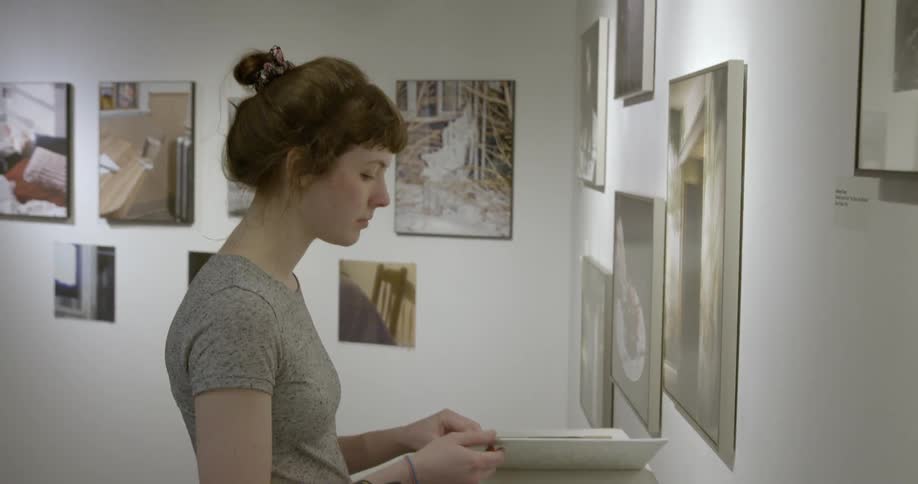 A woman turns the pages of a book in an art gallery